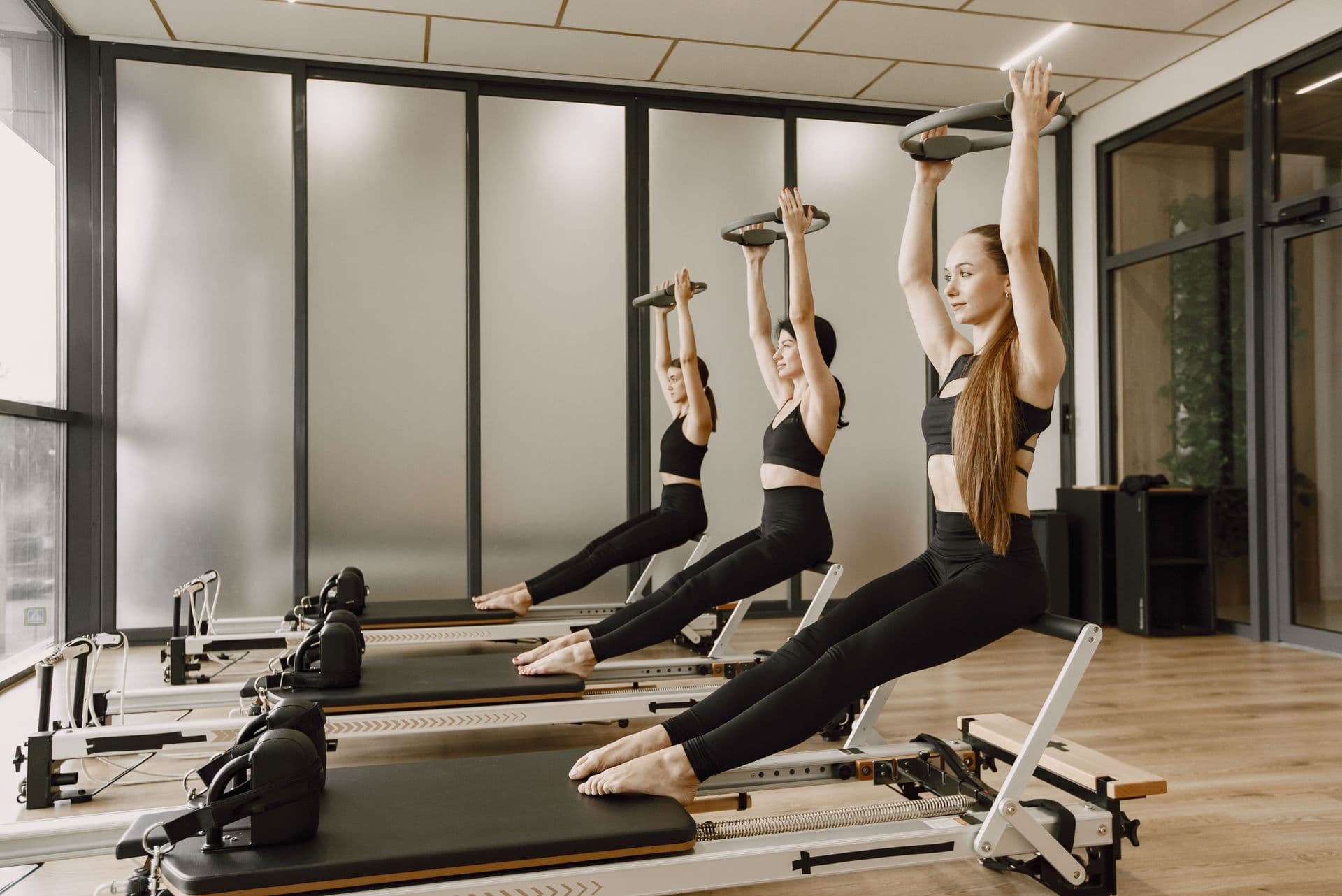 Tres alumnas trabajando en sincronía sobre los reformers de Línea Pilates Studio