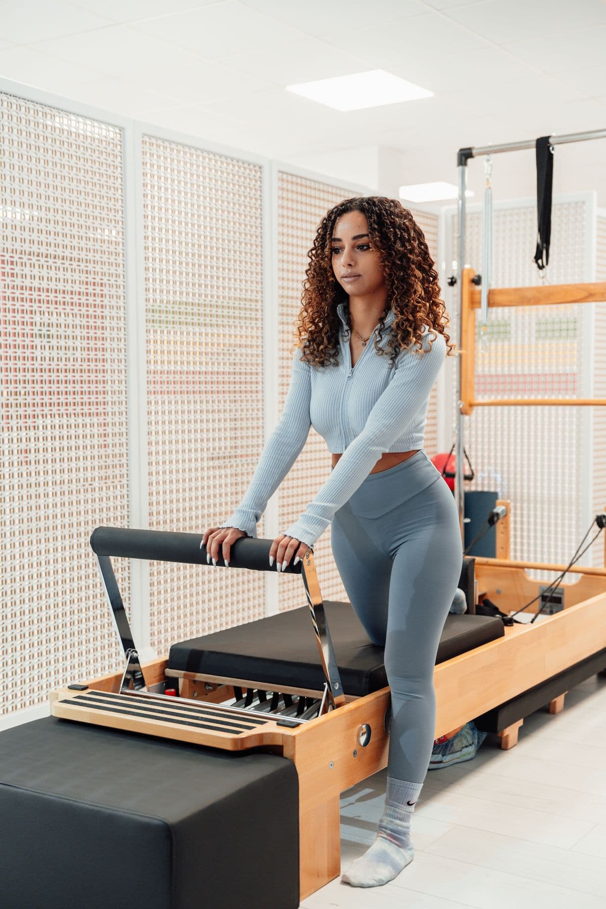 Alumna apoyada en la torre de un cadillac de pilates